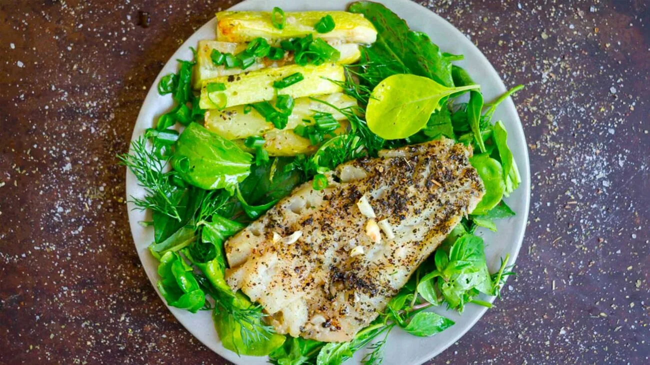 Fish served with salad on a big white plate