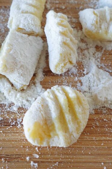 Freshly made potato gnocchi on a board.