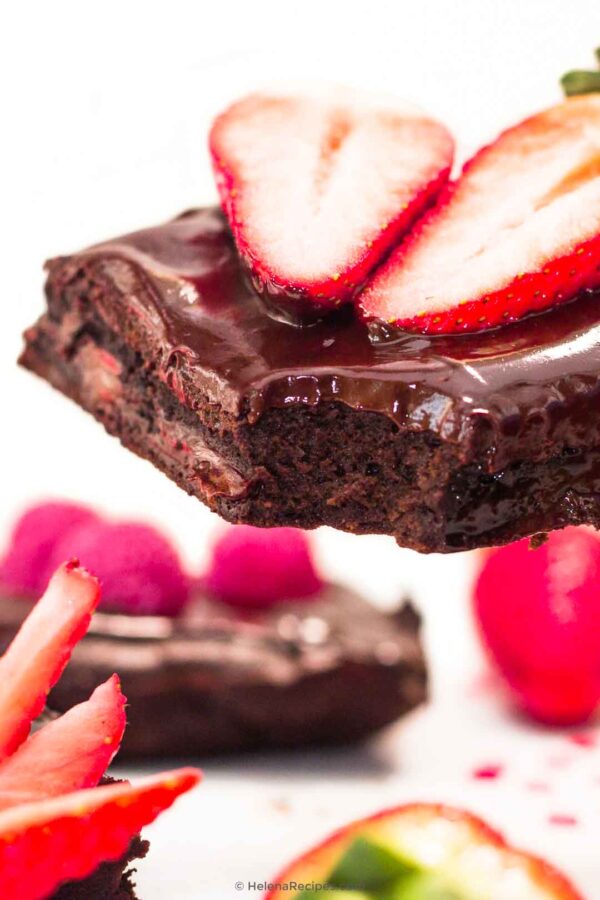 Closeup on the Double Chocolate Brownies with one bite missing and two halves of a strawberry on top