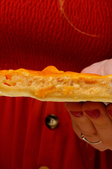 A piece of shrimp quiche in two hands
