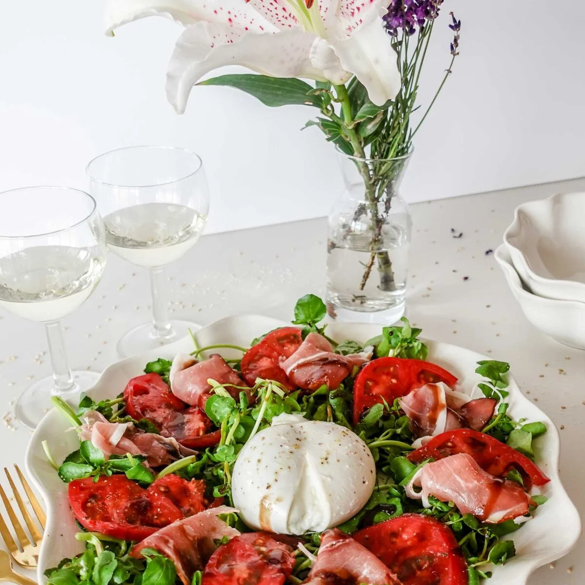 A closeup of Watercress Tomato Salad on a plate with wine