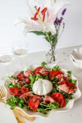 A closeup of Watercress Tomato Salad on a plate with wine