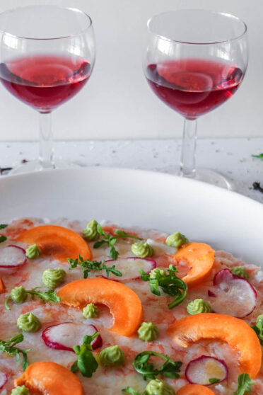 Apricot Shrimp Carpaccio on a plate with two glasses of port wine