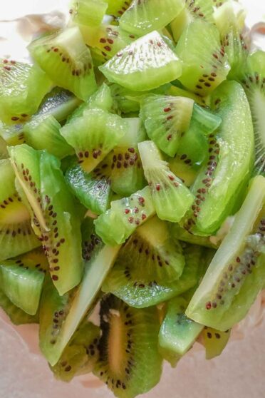 Kiwi Pavlova on a plate with icing sugar