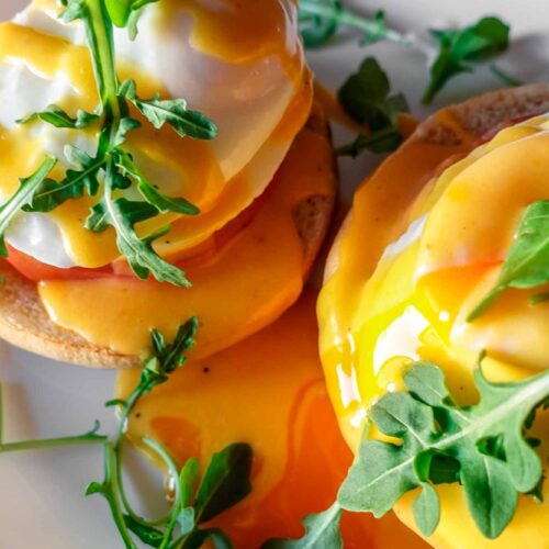Caprese Eggs Benedict on a plate with arugula and running egg