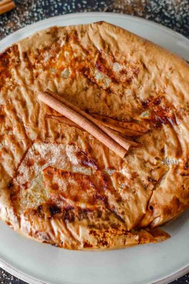 Apple Cinnamon cake on a plate with a cinnamon stick on top.