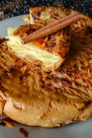 Apple Cinnamon cake on a plate with a cinnamon stick on top.