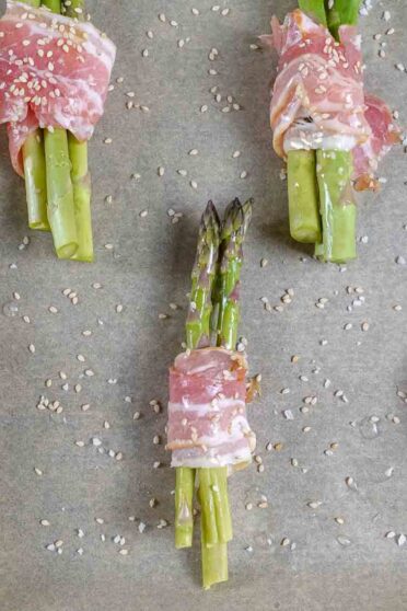 Bacon Wrapped Asparagus Recipe on a baking paper on a tray.