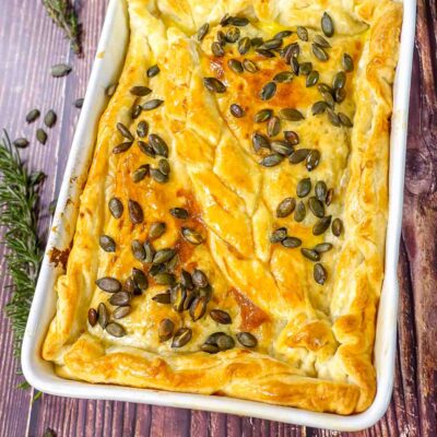 Baked leek and mushroom pie in a form on a table.