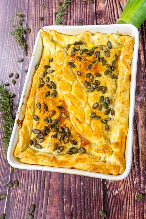 Baked leek and mushroom pie in a form on a table.