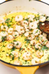 Shrimp in a pan with olive oil with a spoon.