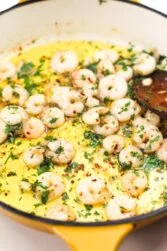 Shrimp in a pan with olive oil with a spoon.