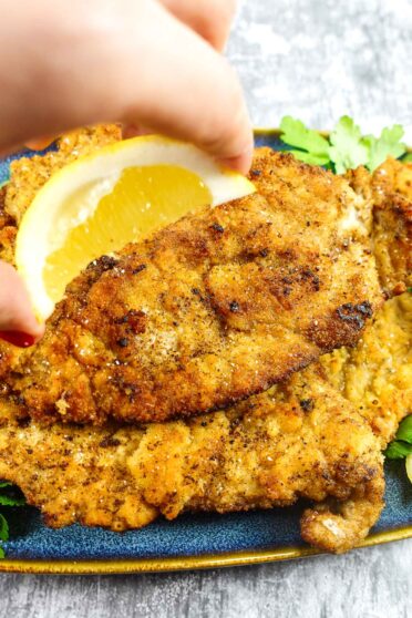 Mediterranean Veal Cutlets on a plate with lemon squeezed on top of the cutlets.