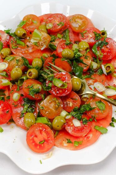 Tomato Salad with olives on a white plate.