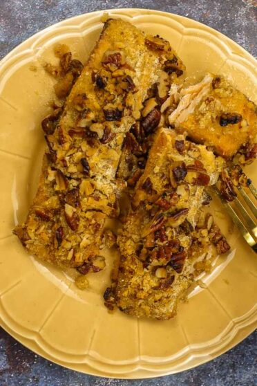 Pecan crusted Salmon on a plate with a fork in one hand.