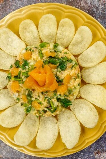 Salmon Tartare on a yellow plate with shrimp chips.