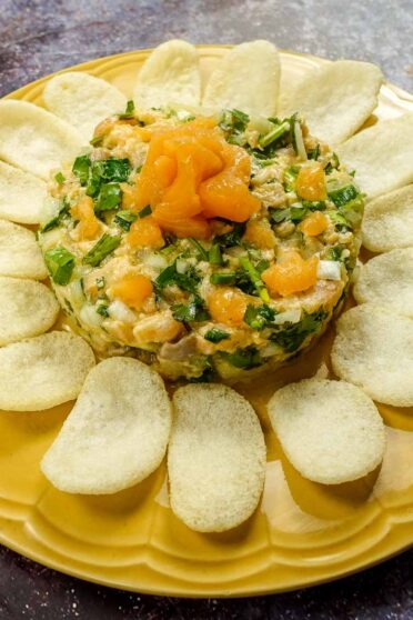 Salmon Tartare on a yellow plate with shrimp chips.