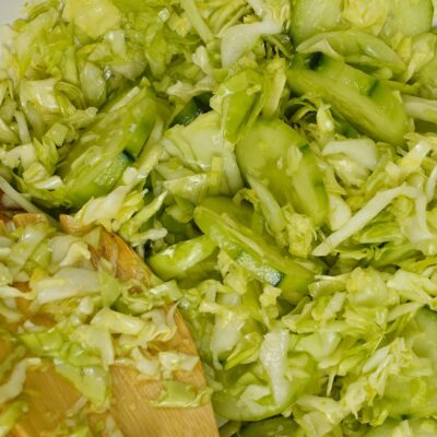 A closeup of Cabbage Cucumber Salad with a spoon and a fork.