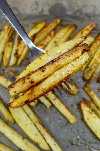 A tray with Oven Baked Fries and a fork full of potatoes.