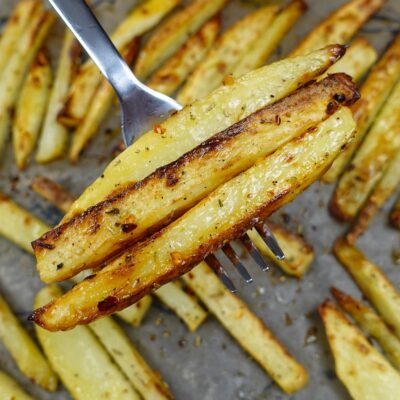 A tray with Oven Baked Fries and a fork full of potatoes.