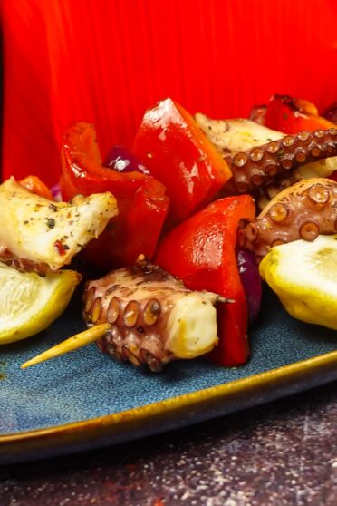 Mouthwatering Grilled Octopus Skewers on a plate with fresh lemon slices.