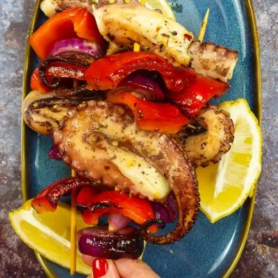 Grilled Octopus Skewers on a plate with fresh lemon slices.
