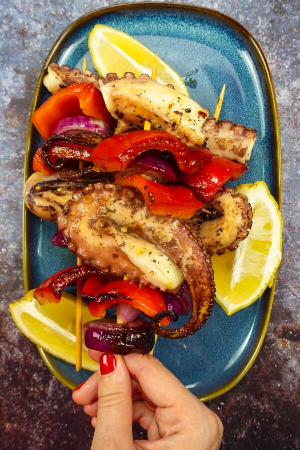 Grilled Octopus Skewers on a plate with fresh lemon slices.