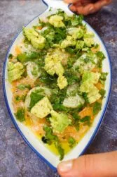 Juicy Salmon Carpaccio with Avocado in a beautiful plat in two hands.