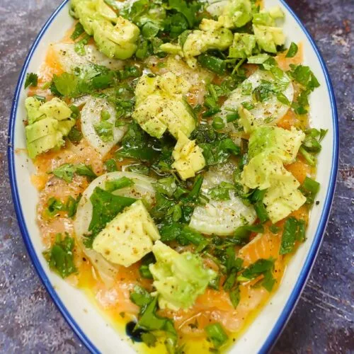 Juicy Salmon Carpaccio with Avocado in a beautiful plat in two hands.
