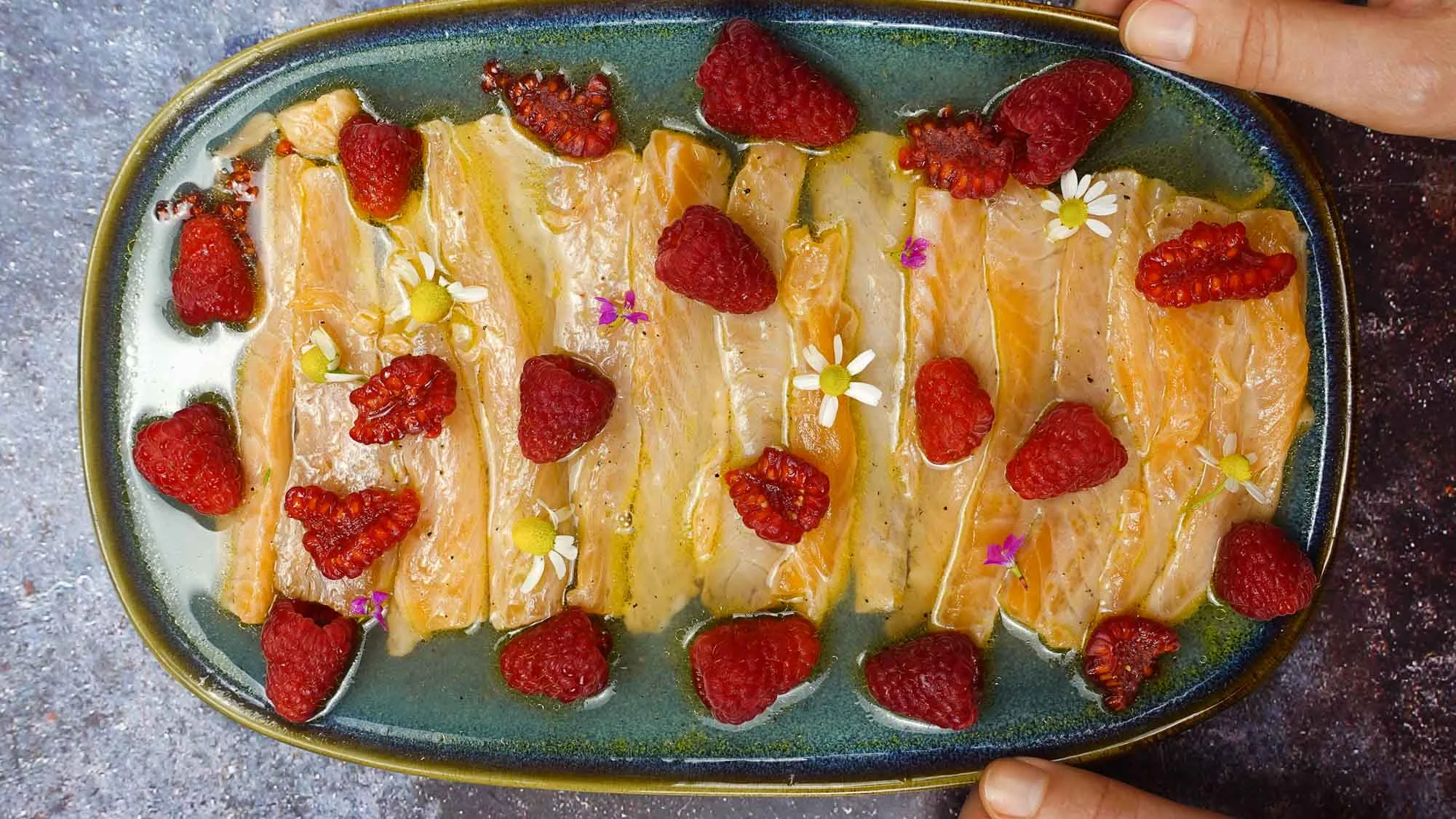 Flavorful Salmon Crudo with Raspberries on a plate.