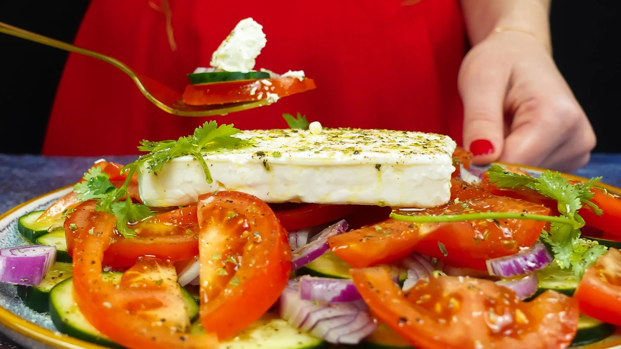 Juicy and delicious Tomato Cucumber Feta Salad on a plate and on a fork in Helena's hand.