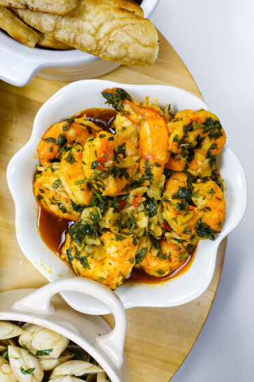 Delicious Portuguese Garlic Shrimp in a white bowl with Madeiran bolo de caco on the side