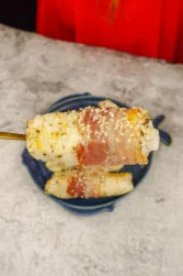 Mediterranean Baked Fish Fillets on a blue plate with a piece of flaky fish