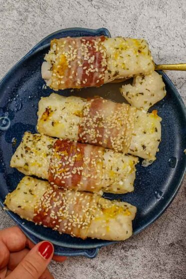 Mediterranean Baked Fish Fillets on a blue plate in two hands