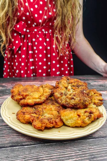 Helena is standing next to plate with breaded beef steak
