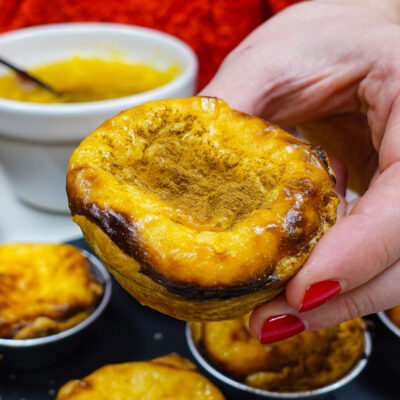 Holding a Pastel de Nata - one of the many Pastéis de Nata or Portuguese Custard Tarts made at home.