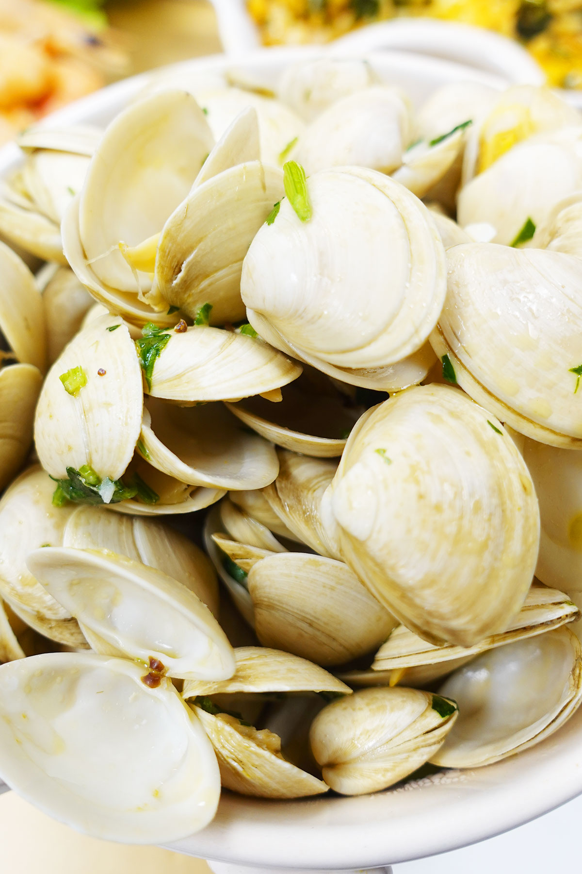Steamed clams with herbs served in a white bowl.