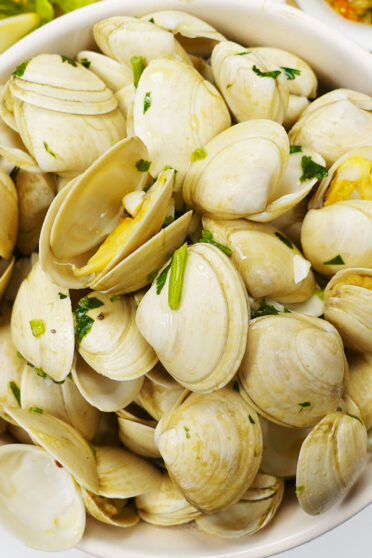 Open Steamed Clams in Wine with garlic and cilantro in a bowl on a board