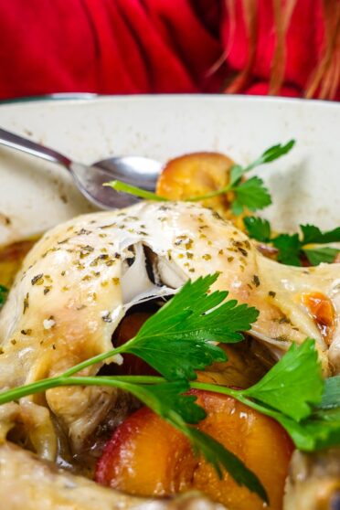 Helena is standing behind the dutch oven pot with chicken