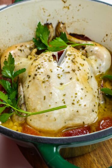 A pot with ready chicken with plums and parsley on top