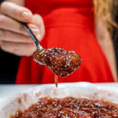 Helena is holding a spoon of fig jam in the right hand