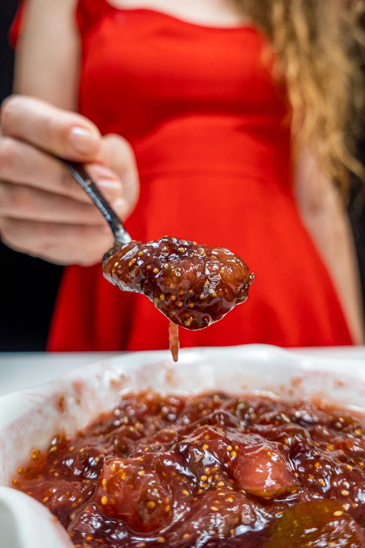 Helena is holding a spoon of fig jam in the right hand