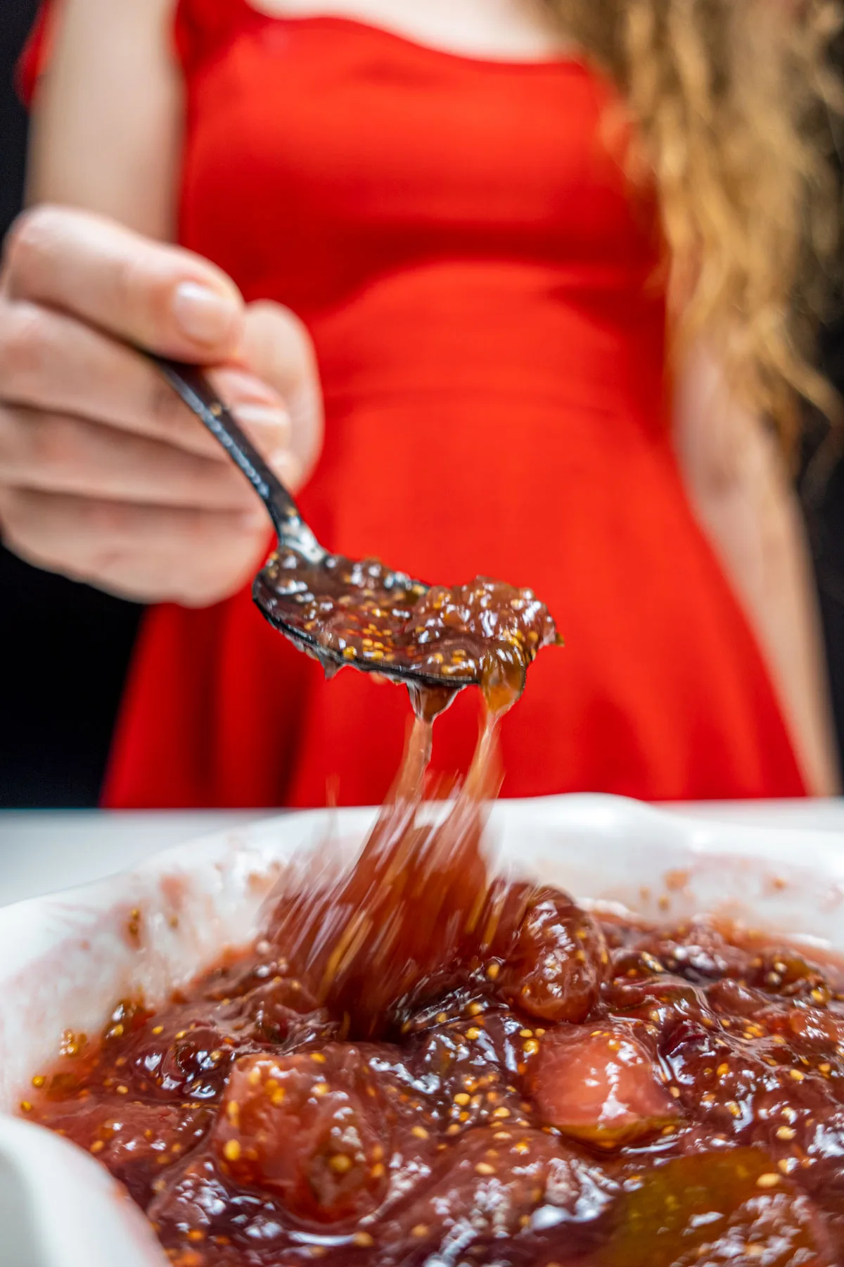 A bowl of thick Mediterranean Fig Jam and Helena is keeping one spoon full of jam
