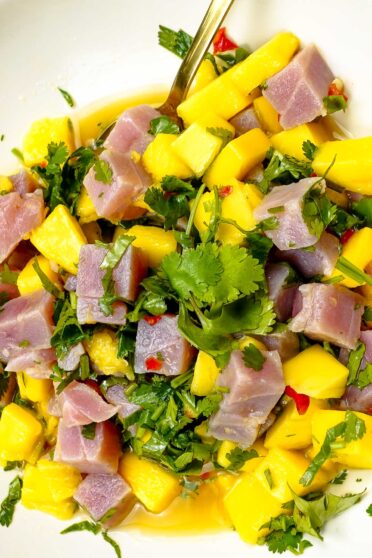 Delicious Tuna Ceviche with Mango in a bowl with a full fork