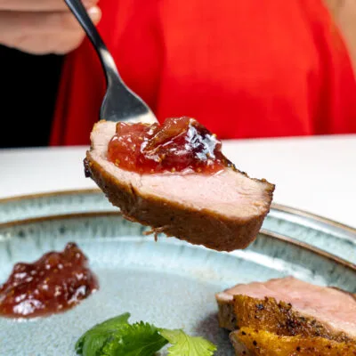Pan Fried Duck Recipe with fig jam on top of one piece on a plate with fresh cilantro