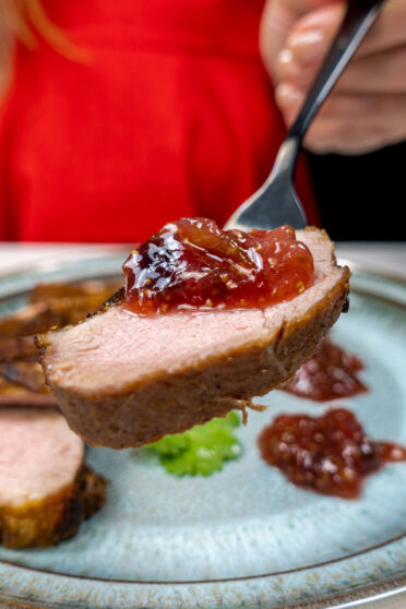 A piece of pan fried duck with fig jam on top.