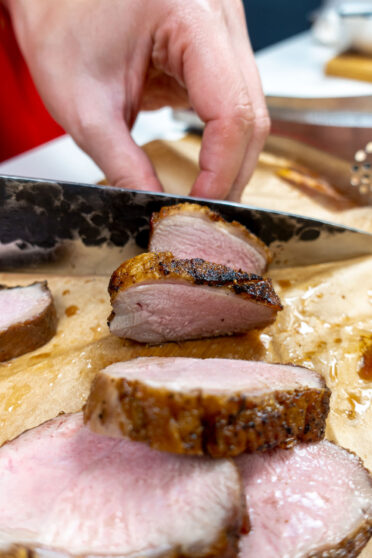 Helena is cutting duck breast on a board with knife