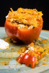 A big red beef stuffed pepper with a hat of pepper on a plate