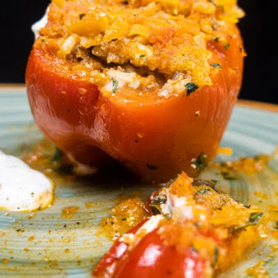 A big red beef stuffed pepper with a hat of pepper on a plate