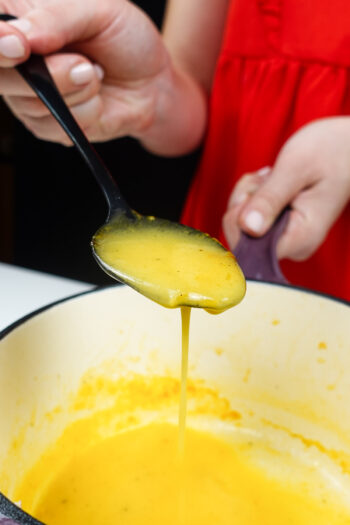 A closeup of one spoon of Beurre Blanc Sauce with Saffron in Helena's hands